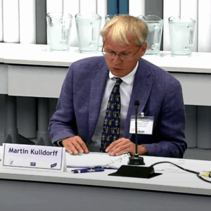 A blonde man with glasses seated at a table.